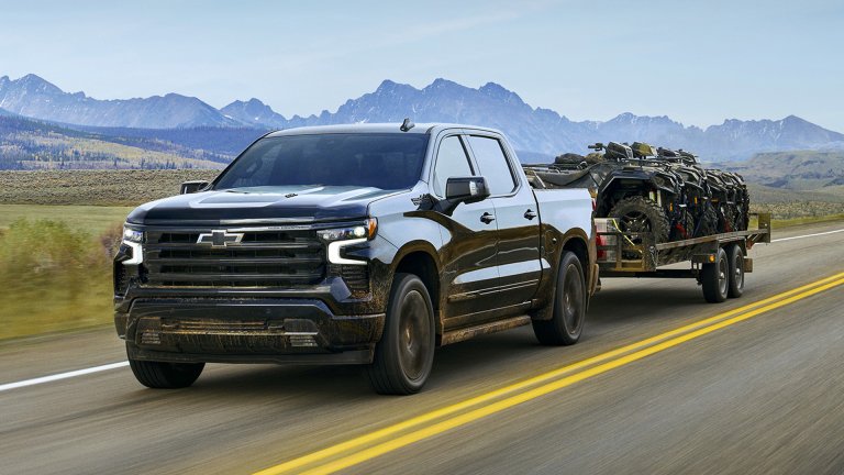 A Chevrolet Silverado pickup truck tows a trailer loaded with ATVs.